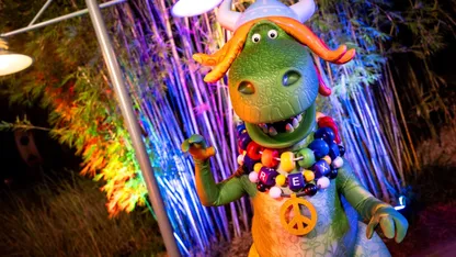 Partysaurus Rex from the Toy Story franchise at Jollywod Nights with a peace sign and beads saying "Rex"