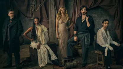 Four people in period clothing pose inside a dimly lit ship’s cabin.