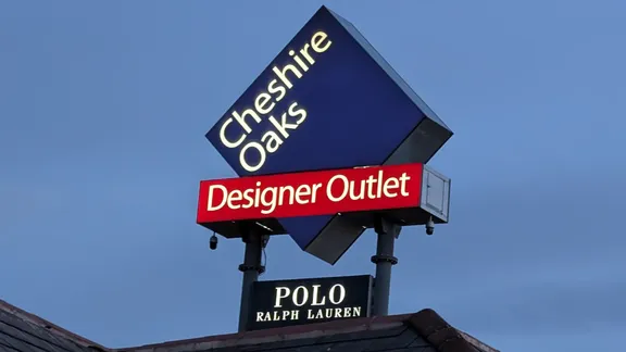 Cheshire Oaks Designer Outlet sign with a Polo Ralph Lauren shop sign beneath.