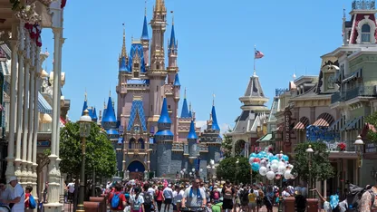 Cinderella Castle viewed from Main Street, U.S.A., with crowds and balloons in the foreground.