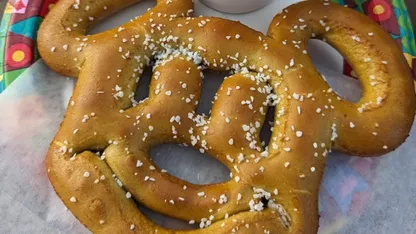 Soft pretzels sprinkled with coarse salt on a colourful patterned surface