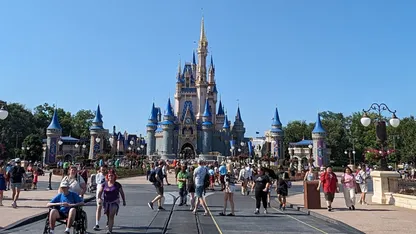 Cinderella Castle at Walt Disney World’s Magic Kingdom, with visitors walking along Main Street under a clear blue sky.