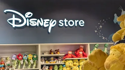 Disney Store display with illuminated logo, shelves of plush toys, and character merchandise.