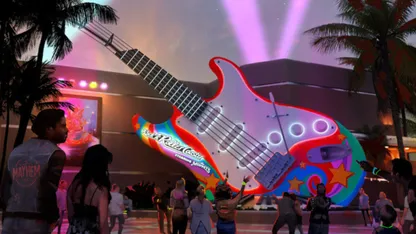 Crowd gathered around a giant, brightly coloured electric guitar sculpture beneath palm trees at an evening event.