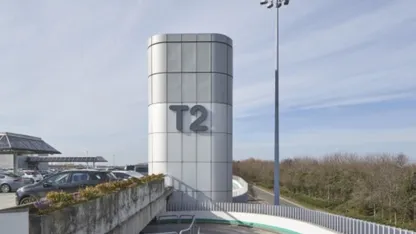 Airport terminal tower marked “T2” overlooking the car park and surrounding landscape.