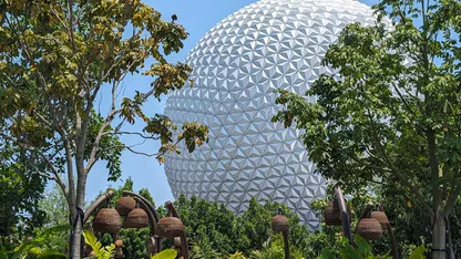 Epcot's Spaceship Earth with trees and hanging baskets in the foreground