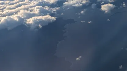 Aerial view of clouds casting shadows over a coastline and sea.