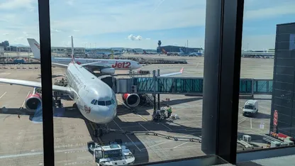 Jet2 aircraft parked at an airport gate, viewed through terminal windows.