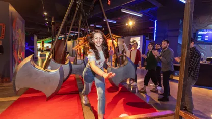 A woman runs down a red carpet in an indoor attraction