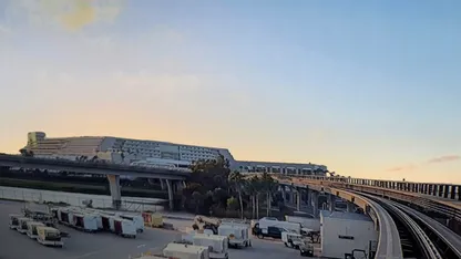 A view of an airport with a bridge, vehicles, and a sunset sky