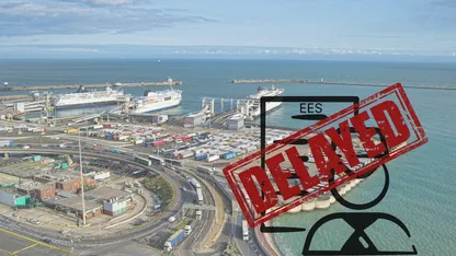Aerial view of a harbor with ships and trucks, with a red sign saying "EES DELAYED"