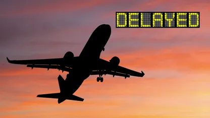 Silhouette of an aeroplane against a sunset with the word “DELAYED”.