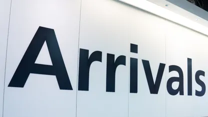 Arrivals sign on a white airport wall.