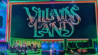 Villains Land sign on a stage set with performers below.