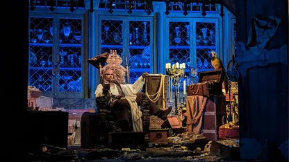 Captain Jack Sparrow sitting in a chair drinking surrounded by treasures