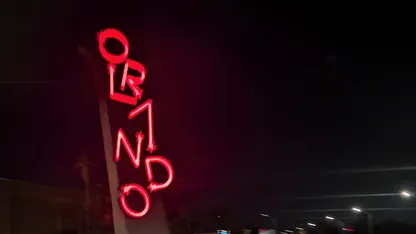 Vertical red neon sign spelling “ORLANDO” at night.