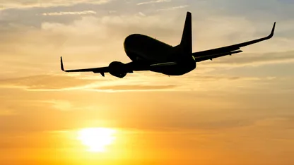 A plane silhouette flying against a sunset sky