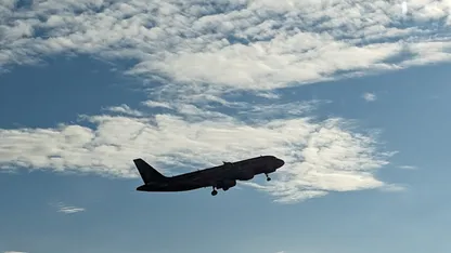 Airplane flying overhead against a blue sky with scattered clouds.