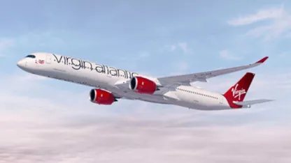 Virgin Atlantic passenger plane flying through a partly cloudy sky.