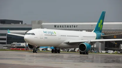 Aer Lingus plane on the runway at Manchester Airport with a cloudy sky in background