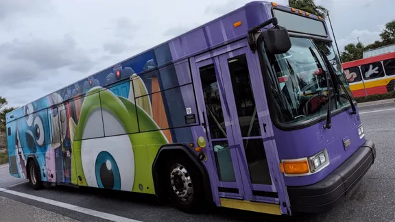 Purple city bus with cartoon character wrap on the side