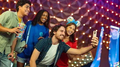 A group of people are taking a selfie in front of a colorful background