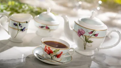 A tea set with a teapot, cup, saucer, and spoon on a marble table