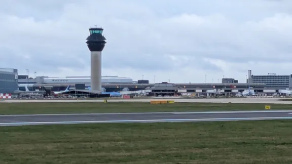 Airport control tower beside runway under cloudy sky