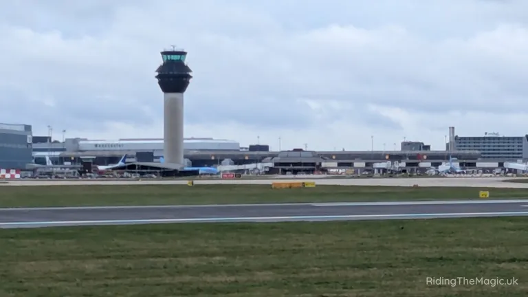Airport control tower beside runway under cloudy sky