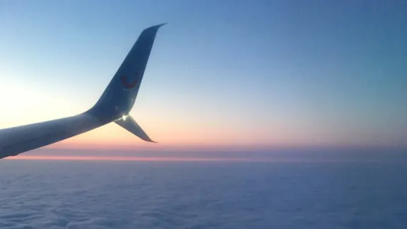 Aeroplane wing above clouds at sunrise or sunset