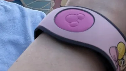 wrist with pink Magic Band on dark pink centre with Mickey Mouse face silhouette