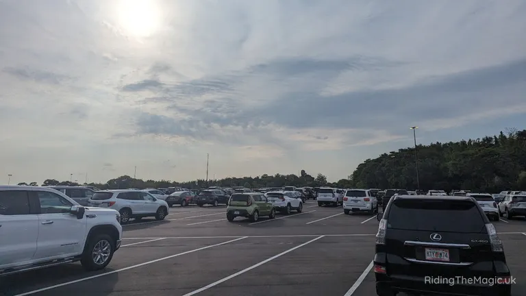 A parking lot filled with many cars, including SUVs, under a cloudy sky