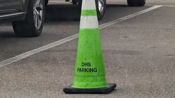 A green and white traffic cone with the words DHS Parking on it