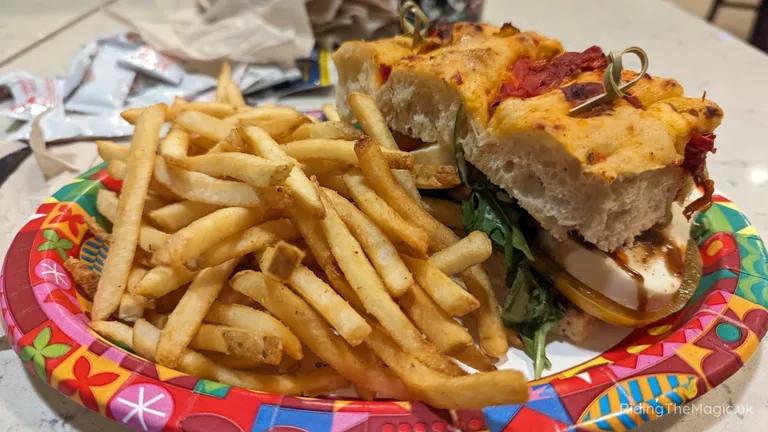A toasted sandwich with salad and sauce, served with a large portion of chips on a colourful plate.
