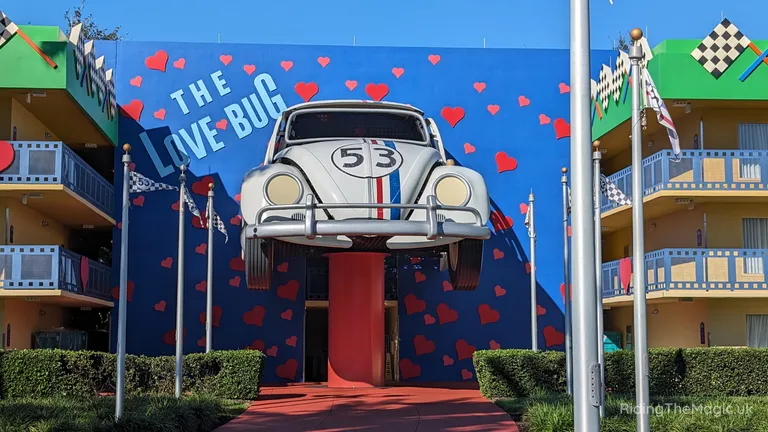 Volkswagen Beetle mounted on a blue mural wall with red hearts and the words “The Love Bug”.