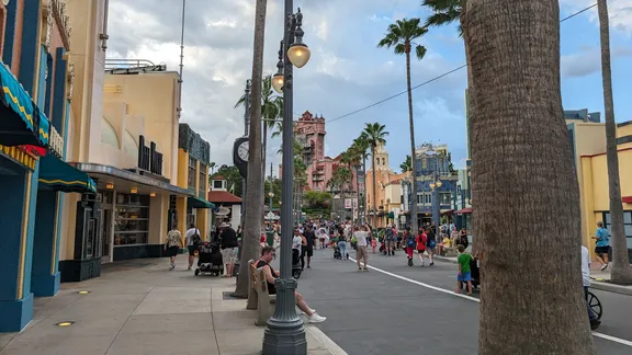 Pedestrian street lined with shops, palm trees, ornate street lamps and colourful Art Deco buildings, busy with people.