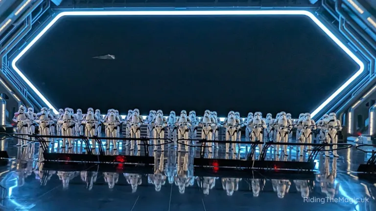 Rows of stormtroopers standing in formation beneath a glowing geometric arch.
