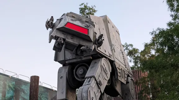 Life-size AT-ST walker from Star Wars, viewed from below in a themed outdoor setting.