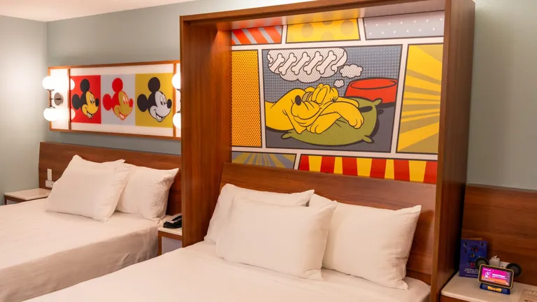Two twin beds with Mickey Mouse paintings on the wall