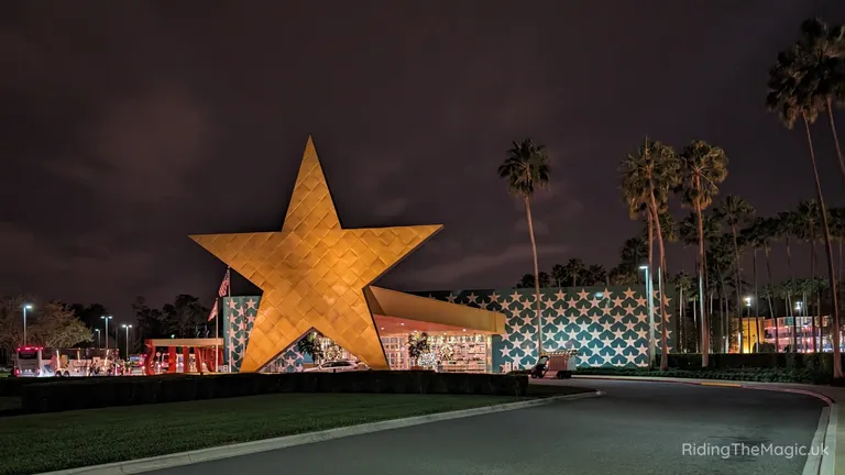 Large gold star-shaped building at night outside a venue with palm trees and star-patterned walls