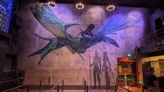 Wall mural depicting a winged creature and silhouetted figures in a dimly lit, purple-lit interior.