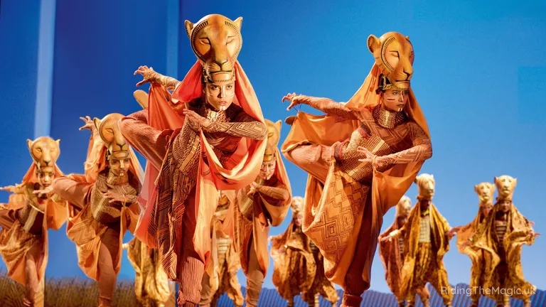 Performers in animal-headed costumes and traditional robes dance outdoors beneath a clear blue sky.