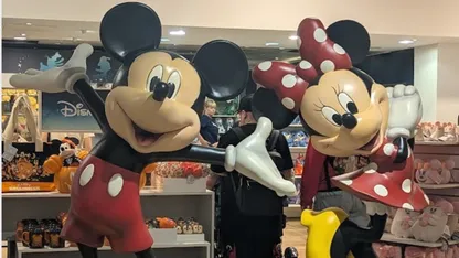 Mickey and Minnie Mouse costumed characters pose together in a Disney shop.