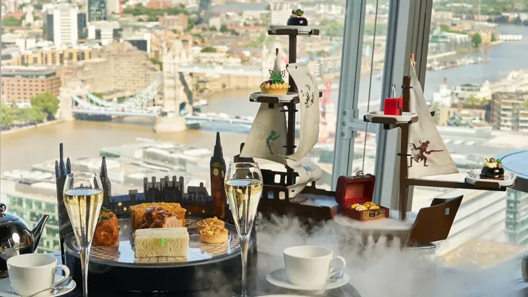 Afternoon tea with champagne, cakes and steaming coffee overlooking a riverside city through floor-to-ceiling windows.