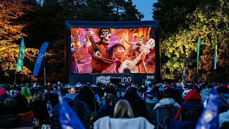 Outdoor audience watching an animated film on a large screen at a public cinema event.