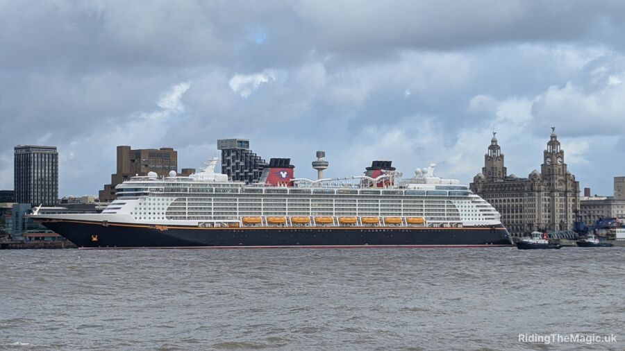 A Disney cruise ship is docked in front of a city skyline