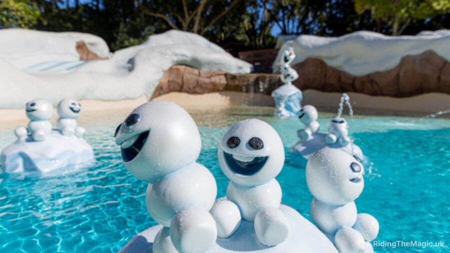 pool crystal blue water in background with three small snow men foregrounded with smiling faces