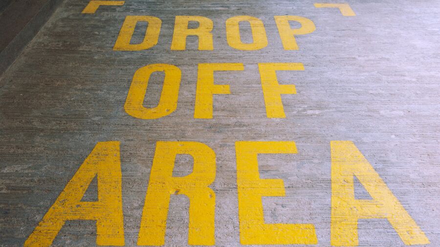 Yellow Drop Off Area text painted on concrete floor at an airport