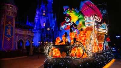 A float with a dragon and Coco playing guitar in front of Cinderella castle