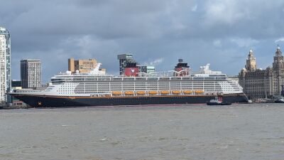 A large cruise ship sailing in the river with buildings on the sides
